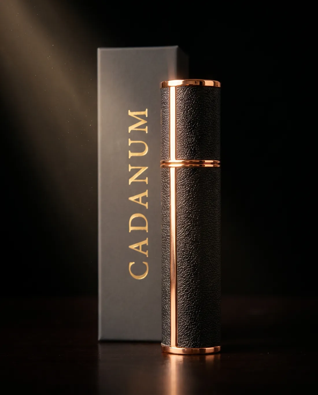 The CADANUM first edition atomizer beside its dark grey gold-foiled box